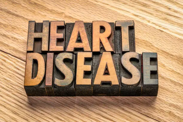 heart disease word abstract in vintage letterpress wood type blocks against grained wood planks, health and well being concept