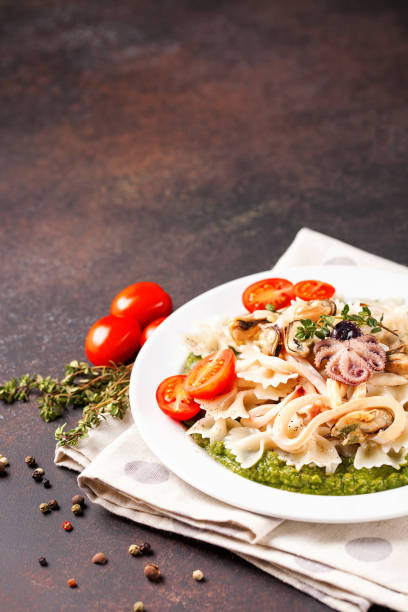 istock Paste with tomatoes, seafood and spinach sauce in a plate on a table. Italian food. Selective focus. Copy space 1210255736