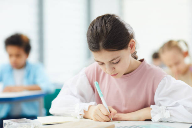 istock Schoolgirl Writing Essay In Class 1210258588
