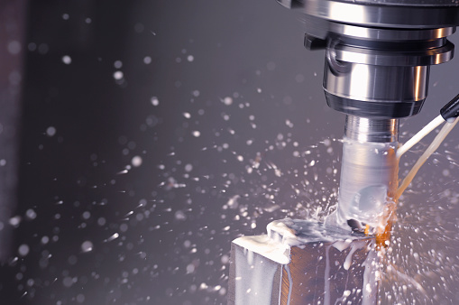 Close up for the automatic cutting machine carving holes in a metal detail at the plant. Metal details production with metal shavings flying into the sides.