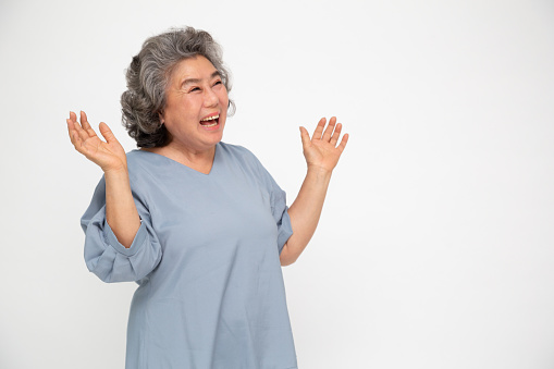 Portrait of excited screaming asian senior woman standing isolated over white background, Wow and surprised concept
