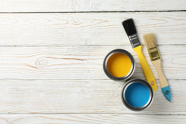 istock Paint cans and brushes on wooden background, top view 1210269440