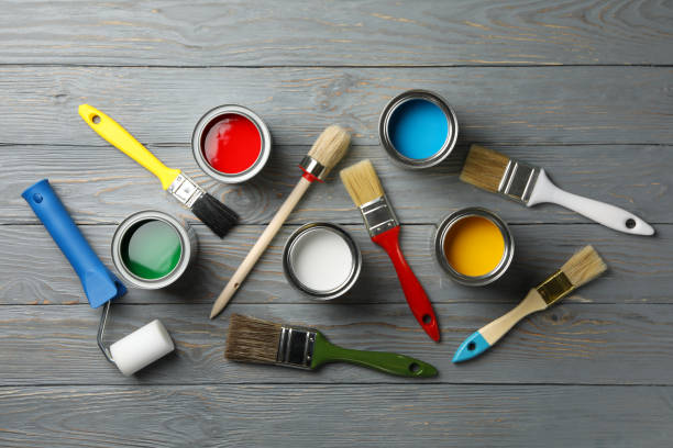 istock Different paints, brushes and roller on wooden background, top view 1210269677