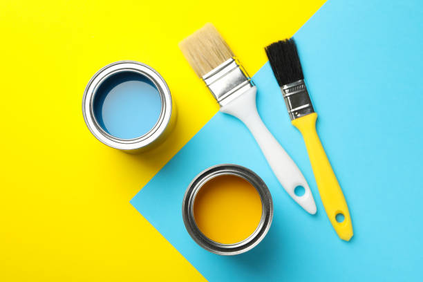istock Cans with paint and brushes on two tone background, top view 1210270135