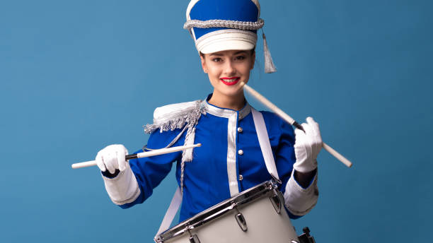 istock Charming cheerful drummer in a blue uniform, sings and plays the drum. 1210278436