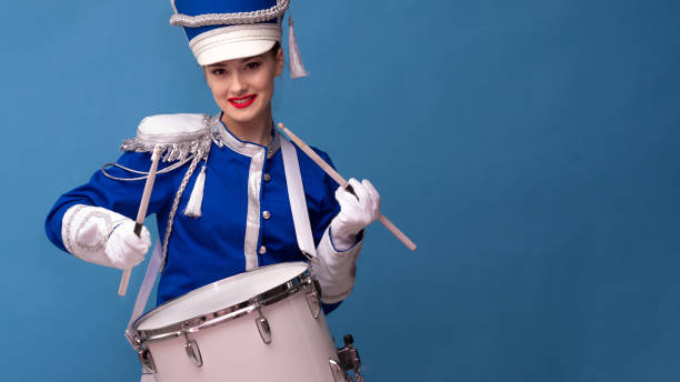 istock Charming cheerful drummer in a blue uniform, sings and plays the drum. 1210279044