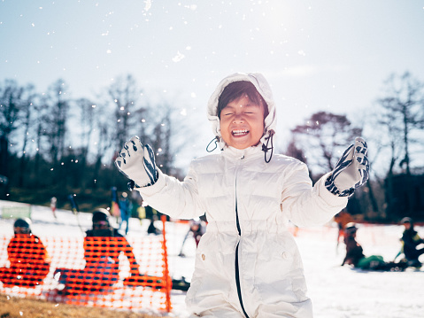 Happy asian kid having fun with snow in winter day in Hokkaido. Japan.