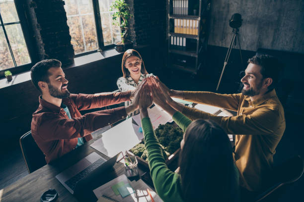 istock Top above high angle view photo professional casual style people sit desk table put highfive stack hands achieve corporate start-up aims goals practice teambuilding seminar office workplace 1210283708