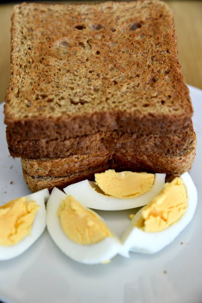 istock Whole wheat slice toasted bread with sliced boiled egg on the white plate for breakfast 1210285537
