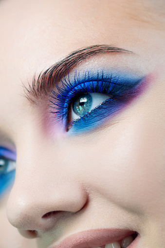 Glamorous bright eye makeup using the trend color classic blue, women's eyes. Close-up of eye makeup, eye shadow in different shades of blue, Blue shadows and earrings