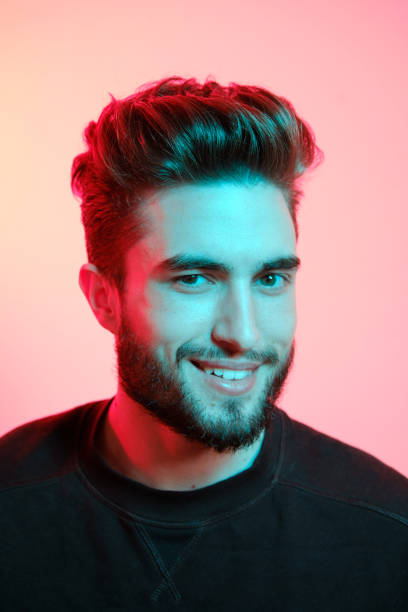 istock Young handsome model posing in a studio in a trendy neon light. Vibrant color. Bright colorful light effects. Disco style. 1210288650