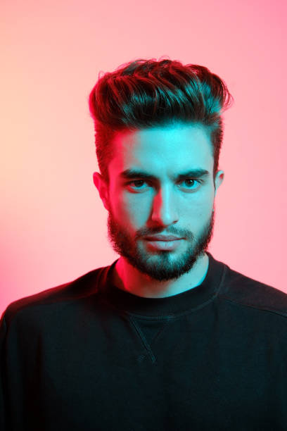 istock Young handsome model posing in a studio in a trendy neon light. Vibrant color. Bright colorful light effects. Disco style. 1210288714