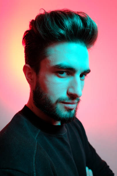 istock Young handsome model posing in a studio in a trendy neon light. Vibrant color. Bright colorful light effects. Disco style. 1210288772