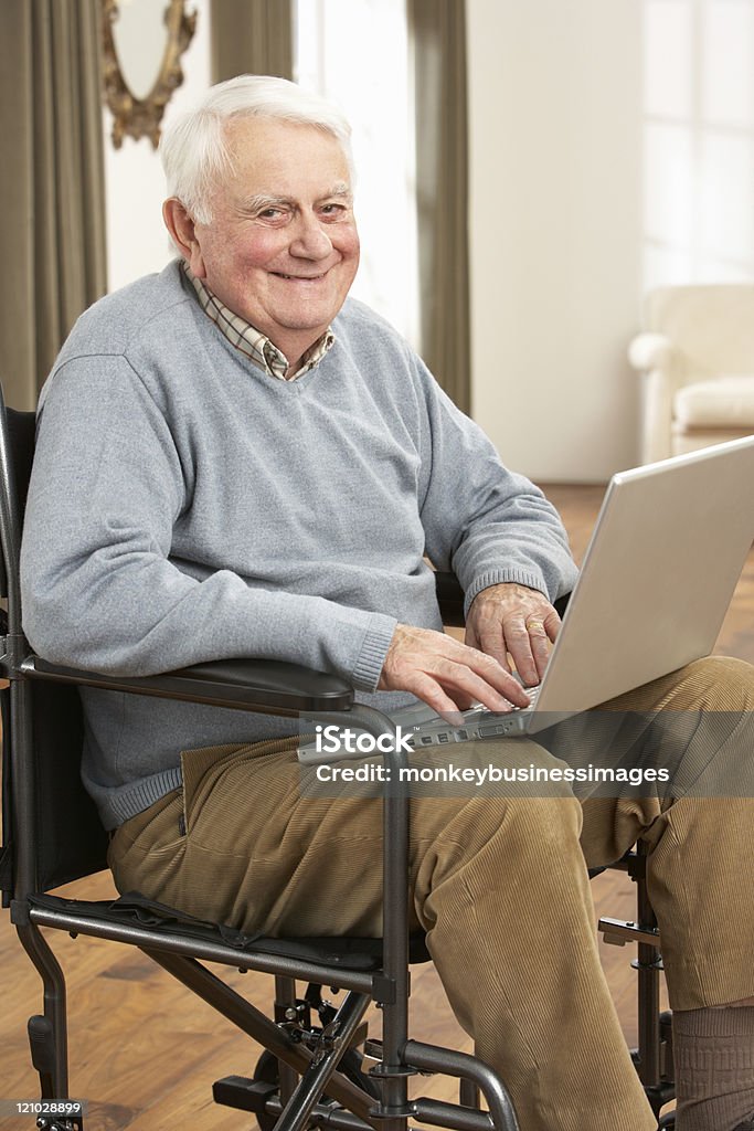 Behinderte Senior Mann, sitzend im Rollstuhl mit Laptop - Lizenzfrei 70-79 Jahre Stock-Foto