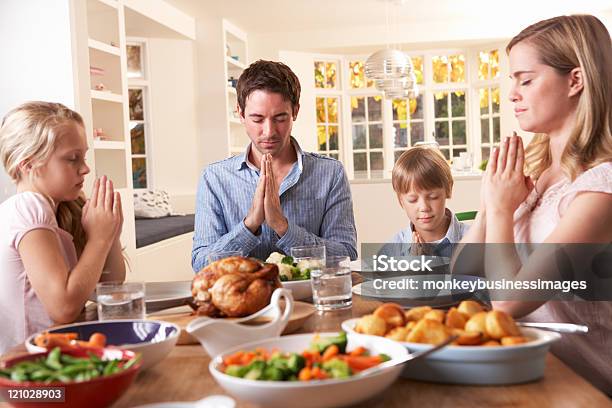Famiglia Dicendo La Preghiera Prima Di Mangiare La Cena Arrosto - Fotografie stock e altre immagini di Cristianesimo