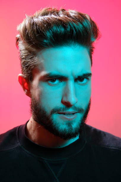 istock Young handsome model posing in a studio in a trendy neon light. Vibrant color. Bright colorful light effects. Disco style. 1210289098