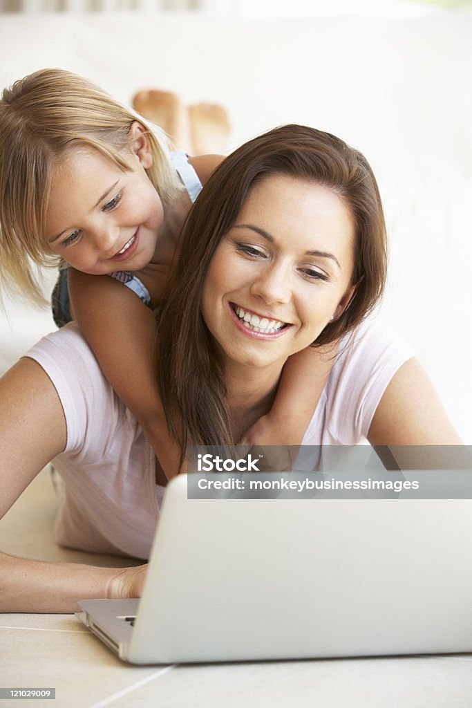 Young mother and daughter using laptop computer Young mother and daughter using laptop computer laying on floor at home Working At Home Stock Photo