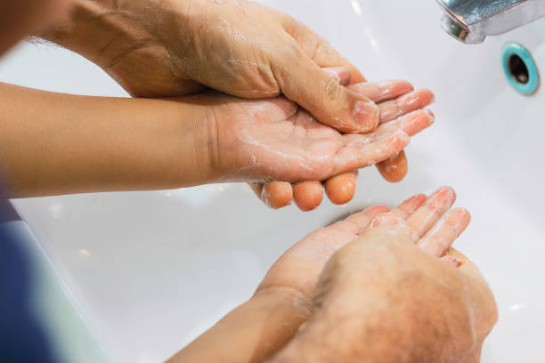 Dad washing his little son's hands with soap and water stock photo