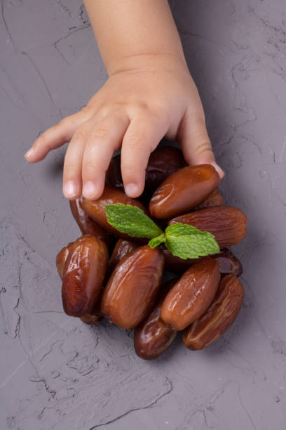 istock Girl holding Ramadan Dates, mint leaf above. Top view and vertical 1210290497