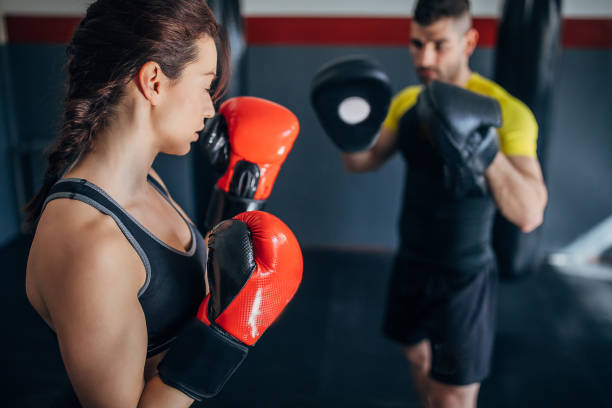 istock Young woman on kick box practice, learning from her coach while sparring with him 1210290621