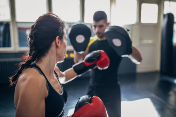 młoda kobieta na treningu kick box, uczenie się od swojego trenera podczas sparingu z nim - kickboxing zdjęcia i obrazy z banku zdjęć