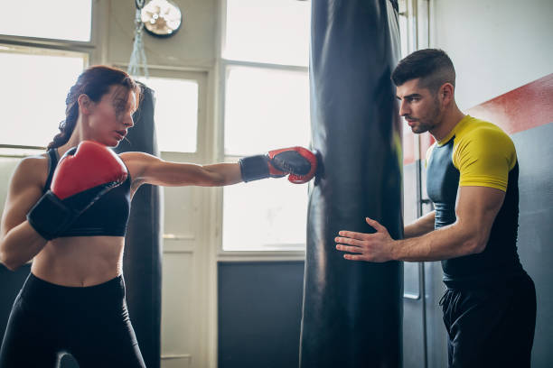 istock Young woman on kick box practice, learning from her coach while sparring with him 1210290806