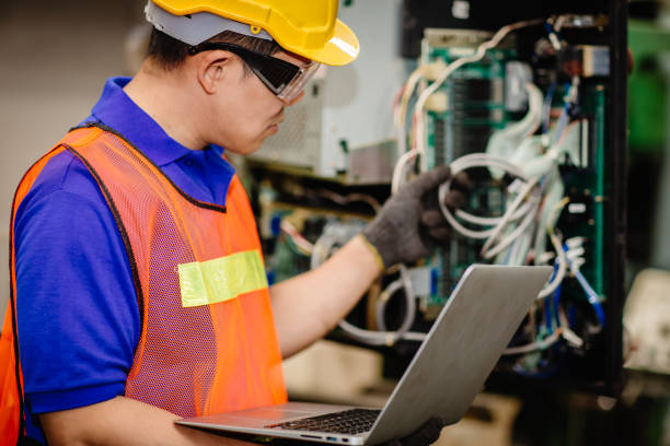 istock Service engineer team working with electronic wire back panel of heavy industry machine for maintenance repair and fix with laptop computer for analysis problems. 1210292702