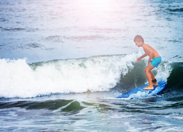 istock Little boy in surfing school learn to surf waves 1210292741