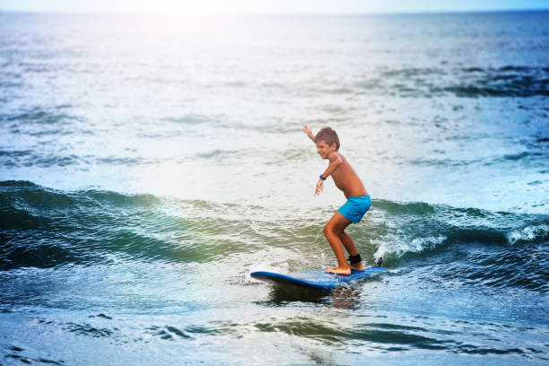 istock Little boy balancing on the surf board in sea 1210292752