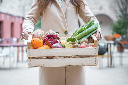 holding a crate with fruits and vegetables