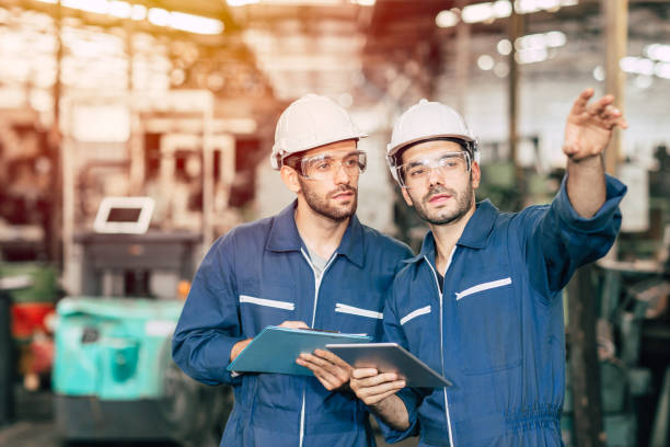 istock Two engineer worker working together with safety uniform and white helmet to work in industry factory handle tablet. 1210293726