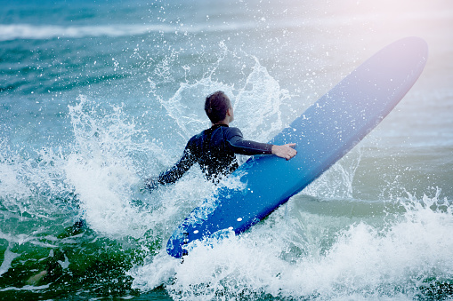 An unrecognizable man, a paddleboard surfer, relaxing on the beach.