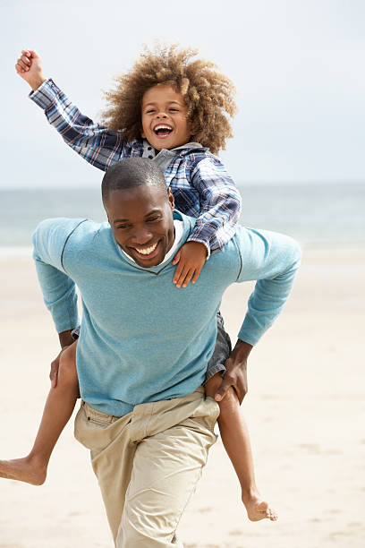 istock Smiling father giving son a piggyback on beach 121029573