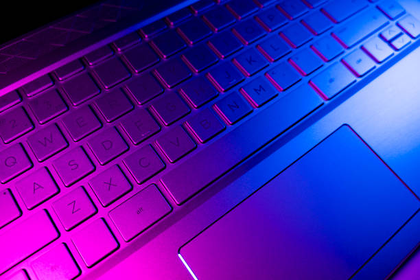istock Close up view of a modern laptop computer keyboard keys. Soft lightning. Computer keyboard close up in pink and blue tones 1210295827