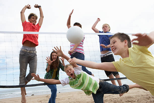 Teenagers playing volleyball on beach