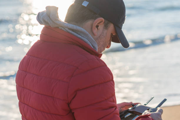 istock Man flying his drone at the beach closeup 1210295930