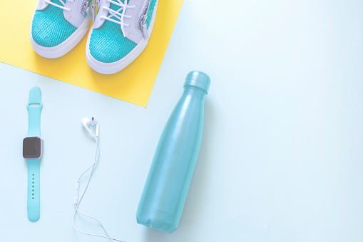 sports accessories flat lay with sneakers, reusable water bottle, head phones and smart watch