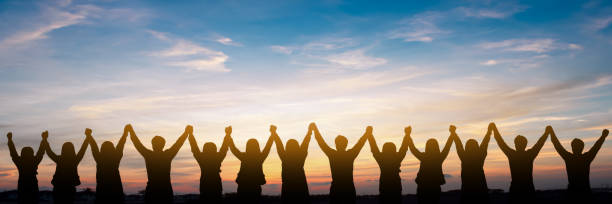 Silhouette of group happy business team making high hands over head in beautiful sunset sky evening time for business success and teamwork concept in company stock photo