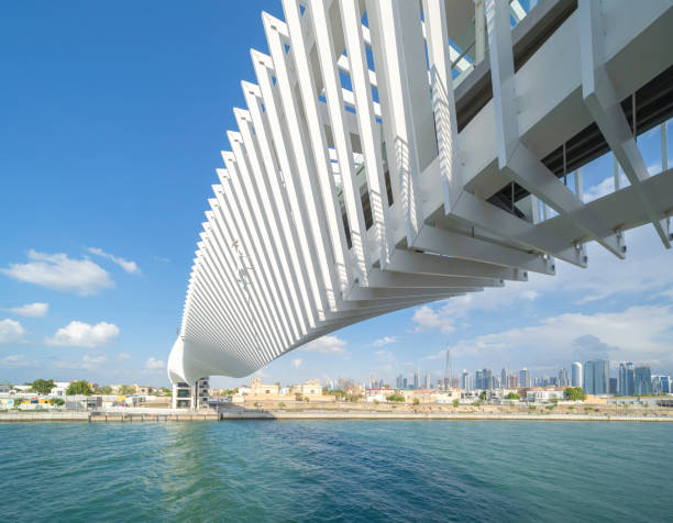 istock Twisted Bridge. Structure of architecture with lake or river, Dubai Downtown skyline, United Arab Emirates or UAE. Financial district and business area in urban city with blue sky background. 1210298771