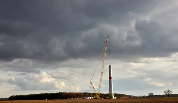 Construction of a wind turbine with an enormous crane, dramatic grey clouds in the background