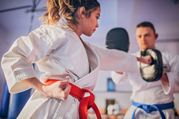 Female karate player practicing with trainer Young female karate player with trainer using focus mitts during training martial arts stock pictures, royalty-free photos & images