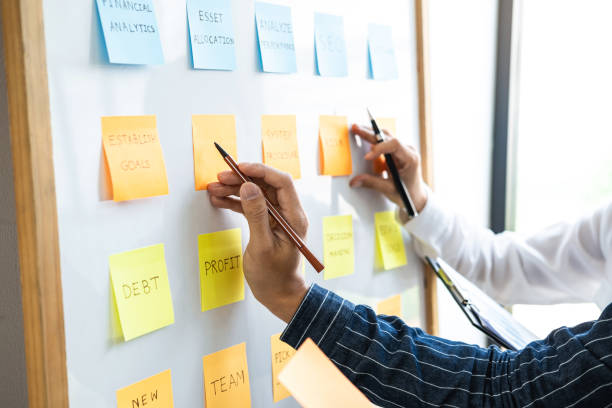 istock Two creative Business people meeting and planning use post it notes sticky note on board to share idea, Analysis data charts and graph with teamwork strategy brainstorming 1210303519