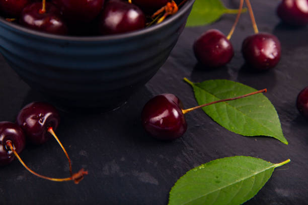 Ripe sweet cherry in a black bowl. Delicious berries.