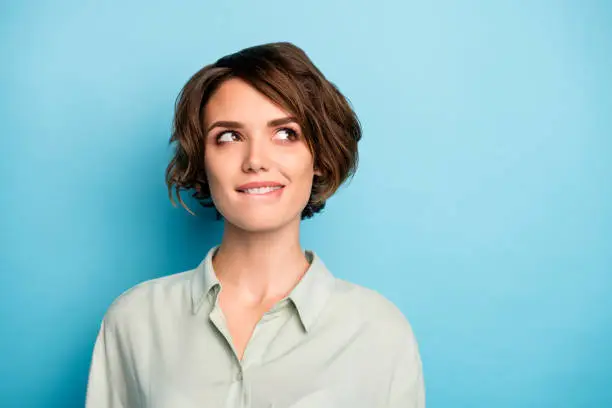 Closeup photo of attractive lady short hairdo wondered look up empty space, biting lips have creative business idea wear casual green shirt isolated blue color background