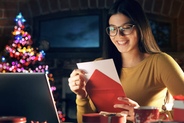 junge frau hält einen umschlag mit einer weihnachtskarte - opening mail letter envelope stock-fotos und bilder