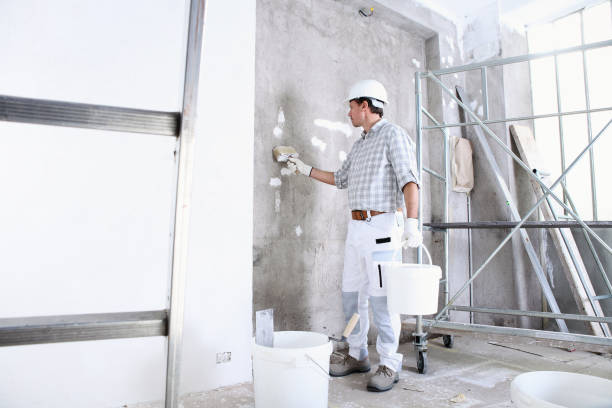 istock plasterer man work holds a bucket and use the brush wet the wall before application to interior construction site wear helmet and protective gloves, ladder and scaffolding on background 1210308523