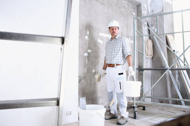 istock plasterer man work holds a bucket and use the brush wet the wall before application to interior construction site wear helmet and protective gloves, ladder and scaffolding on background 1210308534