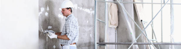 istock plasterer man at work with trowel plastering the wall of interior construction site wear helmet and protective gloves, white wall with copy space and scaffolding on background 1210308554