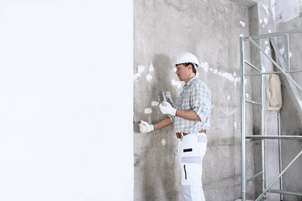 istock plasterer man at work with trowel plastering the wall of interior construction site wear helmet and protective gloves, white wall with copy space and scaffolding on background 1210308557