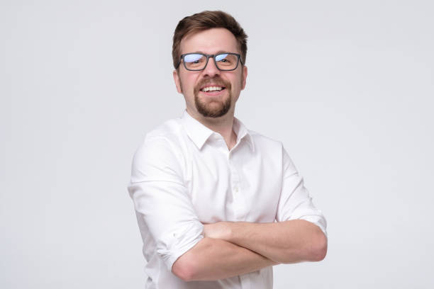 istock Young casual confident man with glasses smiling on white wall. 1210309122